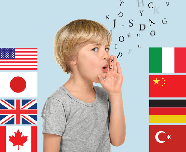 Sprekende kleine jongen, veel letters en verschillende vlaggen op kleur achtergrond. Studeren van vreemde talen - Foto, afbeelding