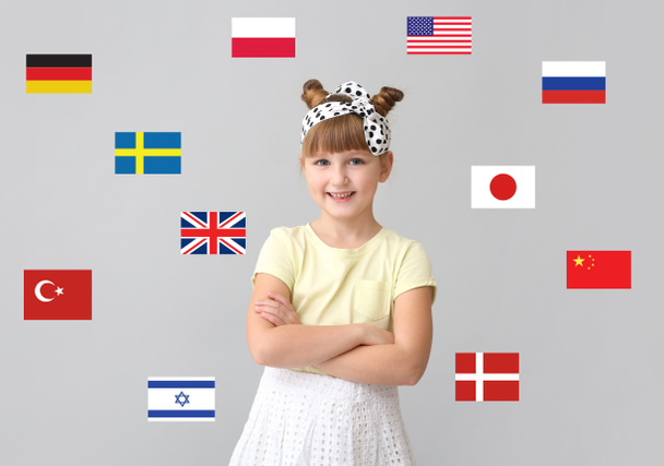 Küçük kız ve farklı ülkelerin bayrakları ışık arka planda. Yabancı dil eğitimi - Fotoğraf, Görsel