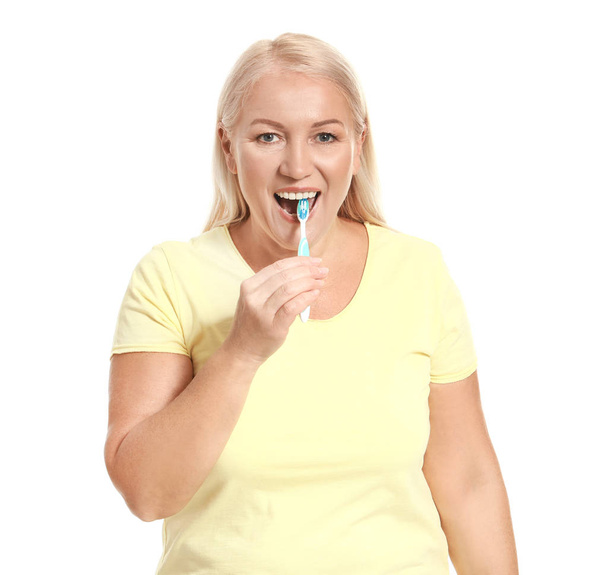 Starší žena čištění zubů na bílém pozadí - Fotografie, Obrázek