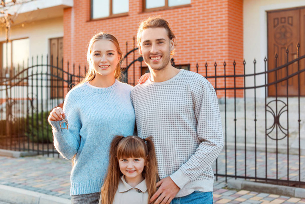 Família jovem com chave perto de sua nova casa
 - Foto, Imagem