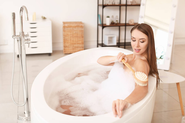 Beautiful young woman washing in bathtub - 写真・画像