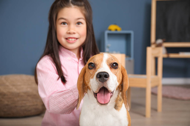 Μικρό ασιατικό κορίτσι με χαριτωμένο σκυλί beagle στο σπίτι - Φωτογραφία, εικόνα