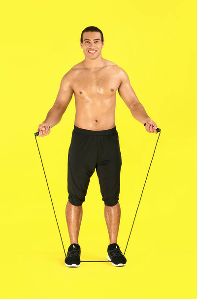 Sporty African-American man with jumping rope on color background - Photo, image