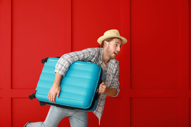 Spieszący się męski turysta z bagażem pod kolor ściany - Zdjęcie, obraz