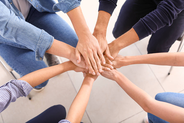 Jovens unindo as mãos durante a sessão de apoio psicológico
 - Foto, Imagem