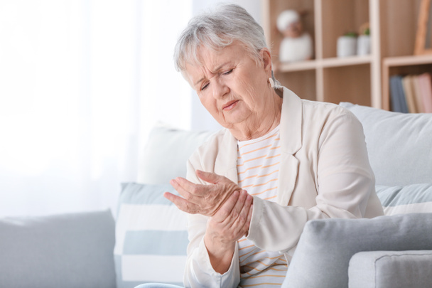 Mulher idosa que sofre de dor no pulso em casa
 - Foto, Imagem