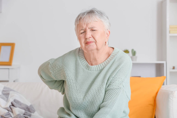 Старшая женщина страдает от боли в спине дома
 - Фото, изображение