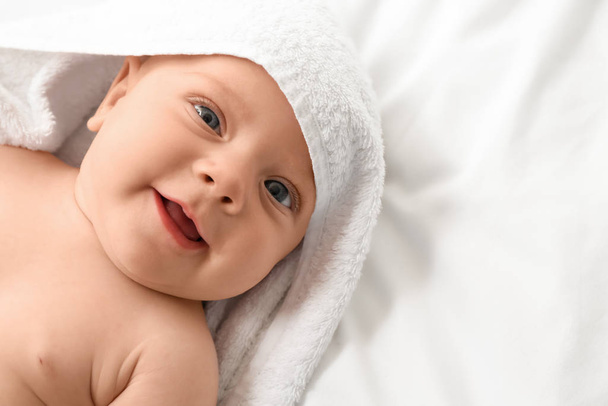 Retrato de bebê pequeno bonito com toalha deitada na cama
 - Foto, Imagem