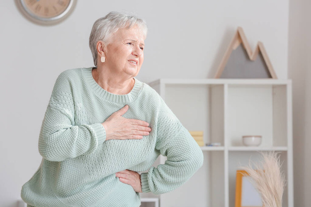 Mujer mayor que sufre de un ataque al corazón en casa
 - Foto, imagen