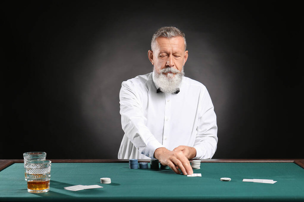 Mature male banker at table in casino - 写真・画像