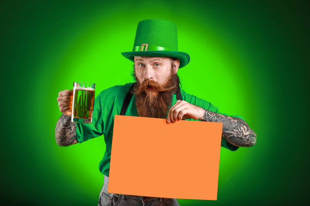 Baard man met lege poster en glas bier op donkere achtergrond. St. Patrick 's Day viering - Foto, afbeelding