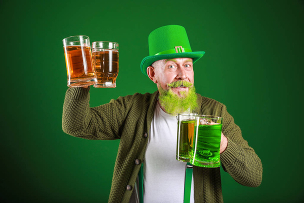 Funny mature man with glasses of beer on dark background. St. Patrick's Day celebration - Foto, afbeelding