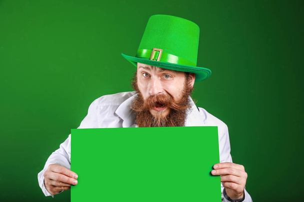Bearded man with blank poster on color background. St. Patrick's Day celebration - Фото, изображение