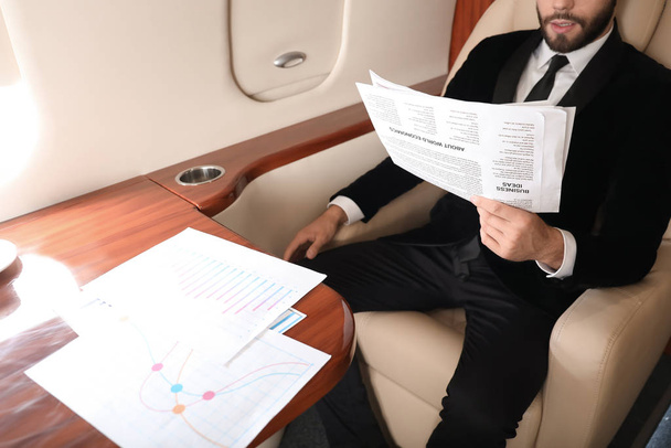 Biznesmen na pokładzie nowoczesnego prywatnego samolotu - Zdjęcie, obraz