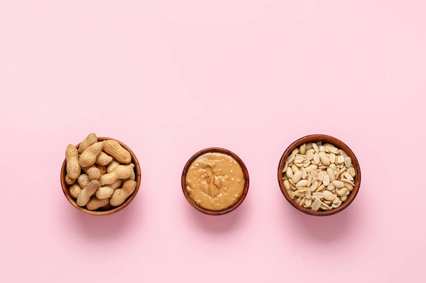 Bowls with peanut butter and nuts on color background - Photo, Image