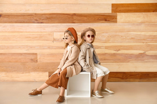 Cute little girls in autumn clothes near wooden wall - Photo, Image