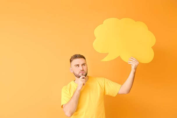 Thoughtful young man with blank speech bubble on color background - Photo, Image