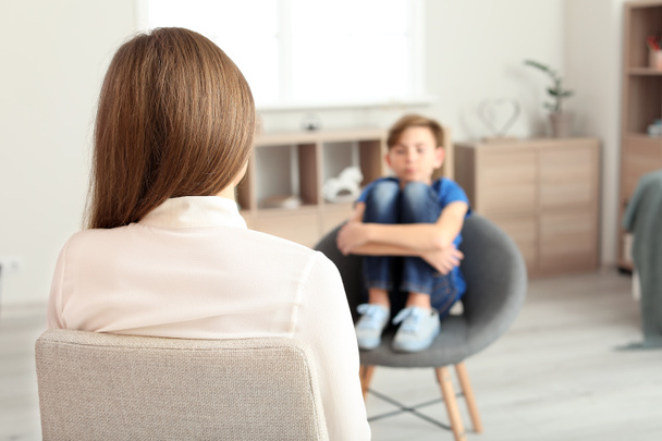 Vrouwelijke psycholoog werkt met jongen in het kantoor - Foto, afbeelding