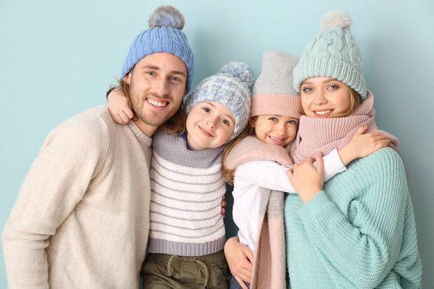 Happy family in winter clothes on color background - Фото, изображение