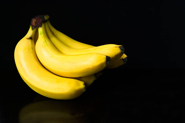 A bunch of bananas isolated on a black background. Copy space. - 写真・画像