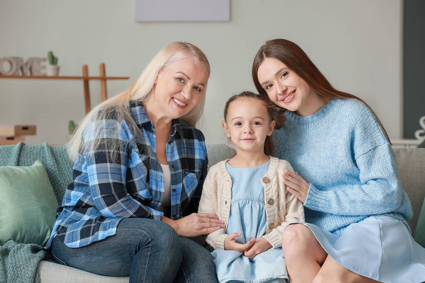 Young woman with her little daughter and mother spending time together at home - Фото, зображення