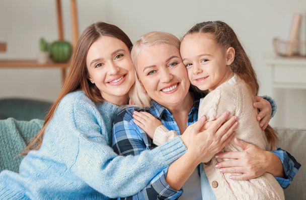 Young woman with her little daughter and mother spending time together at home - Foto, Imagen