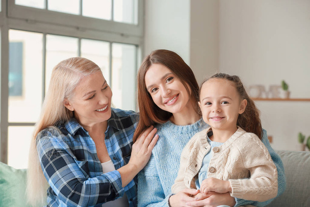 Young woman with her little daughter and mother spending time together at home - Photo, Image