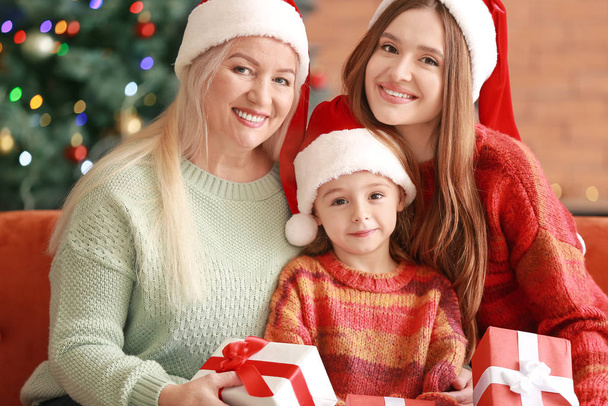Молодая женщина, ее маленькая дочь и мать с рождественскими подарками дома
 - Фото, изображение