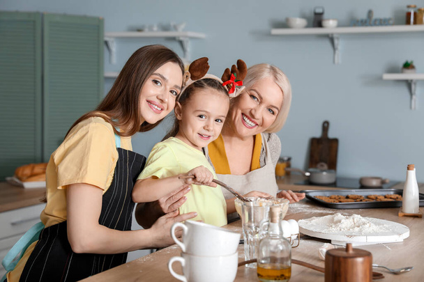 Young woman with her little daughter and mother cooking Christmas cookies at home - Φωτογραφία, εικόνα