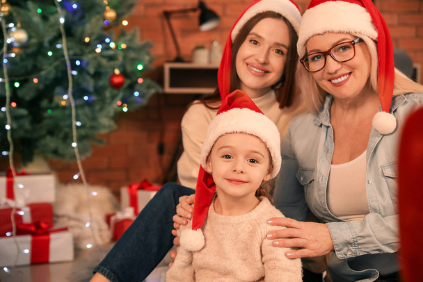 Jeune femme avec sa petite fille et sa mère le soir de Noël à la maison
 - Photo, image