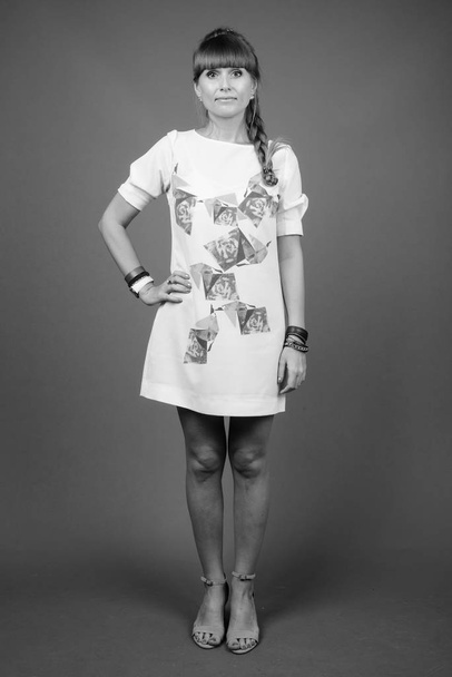 Studio shot of young beautiful woman against gray background in black and white - Valokuva, kuva