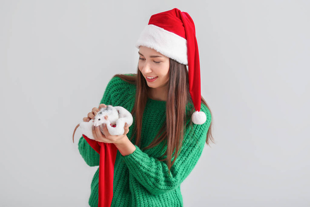 Young woman with cute rat in Santa Claus hat on white background - Фото, изображение