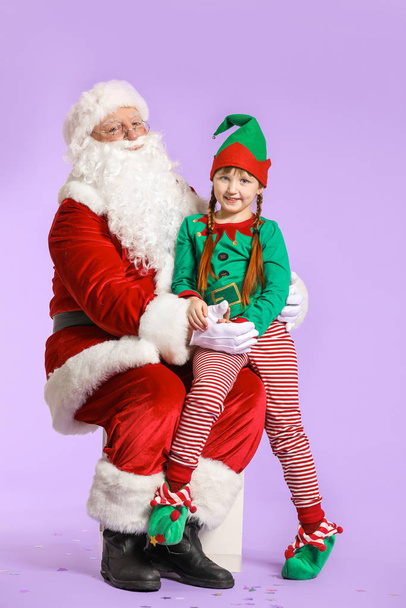 Santa Claus and little elf kid on color background - Фото, изображение