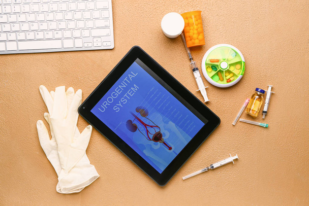 Tablet počítač s obrázkem urogenitálního systému na obrazovce, léky a rukavice na barevném pozadí - Fotografie, Obrázek