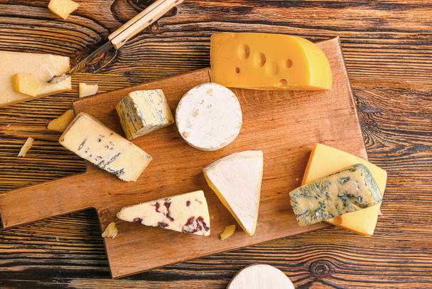Доска с ассортиментом свежих сыров на деревянном столе
 - Фото, изображение