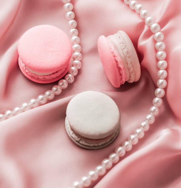 Sweet macaroons and pearls jewellery on silk background, parisia - Photo, Image
