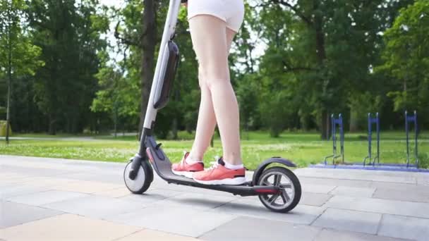 Poten van een meisje, paardrijden op een elektrische scooter in het stadspark. steady shot, slow motion.   - Video