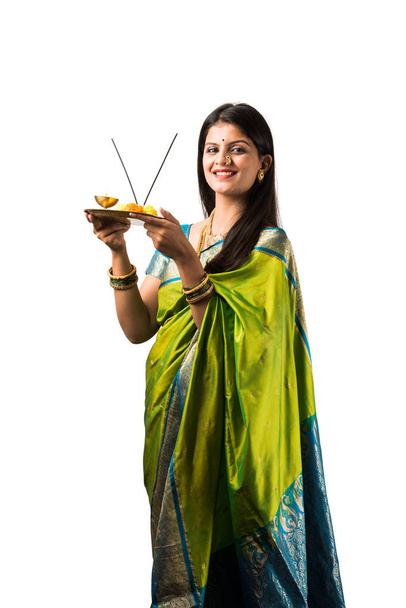 Ινδή νεαρή γυναίκα στο σάρι που κρατά την Πούτζα Θάλι απομονωμένη σε λευκό φόντο, γιορτάζοντας το Ντιβάλι ή το φεστιβάλ ινδουιστών. επιλεκτική εστίαση - Φωτογραφία, εικόνα