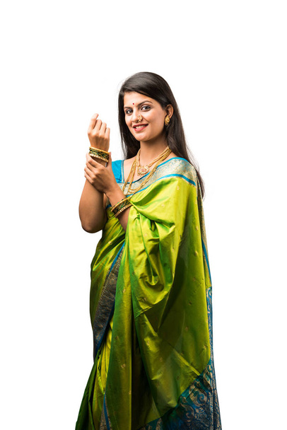 Indian beautiful lady in green saree getting ready for festival of auspicious occasion, wearing gold jewellery, Standing isolated over white background.  - Photo, Image
