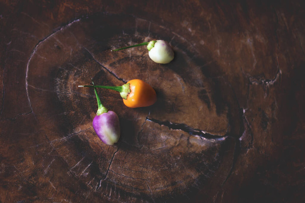 Tricolor chillies em mesa de madeira retro escuro na vista de olhos de pássaros
 - Foto, Imagem