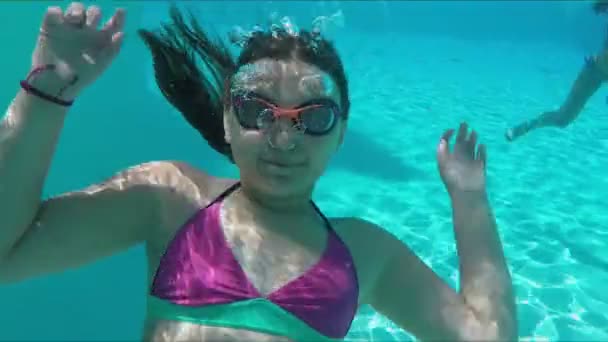 Girl swims underwater in the pool and waves hands - Filmati, video