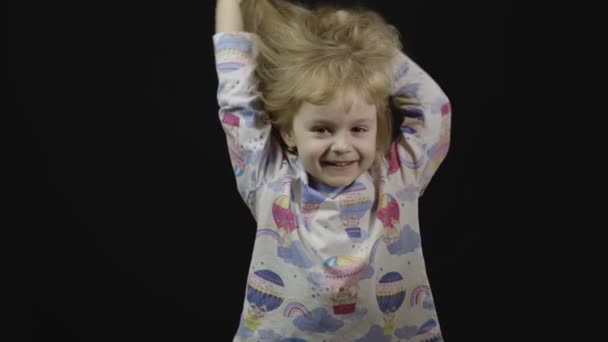 A pizsamás kislány bolondozik és pofákat vág. Fekete háttér - Felvétel, videó