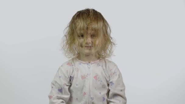 Het kleine meisje in pyjama loopt rond en trekt gezichten. Witte achtergrond - Video