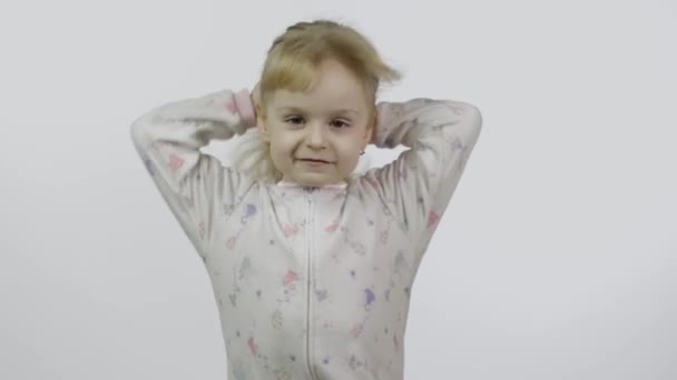Mała dziewczynka w piżamie się wygłupia i robi miny. Białe tło - Materiał filmowy, wideo