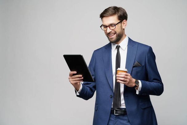 Young Businessman holding digital tablet pc pad and paper cup of coffee - 写真・画像
