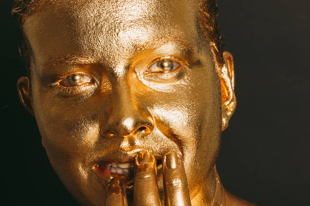 Közelkép fiatal gyönyörű nő borított arany festék - Fotó, kép