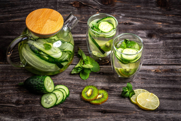 Infused detox water with cucumber, lemon, kiwi and mint for diet healthy eating and weight loss with copy space. healthy lifestyle concept - Photo, Image