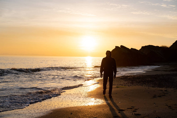 silhouette of male traveler stand near cliff and watch beautiful sunset in the sea - Photo, Image
