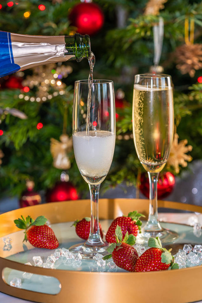 Champagne poured into glasses with strawberries on festive background - Photo, Image