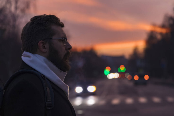 szakállas férfi portré profil arc a nap lenyugvó idő városi stílus környezet fókuszálatlan autók fényszórók háttér - Fotó, kép